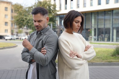 Photo of Man and woman turned away from each other outdoors. Relationship problems