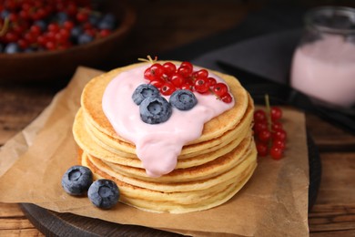 Tasty pancakes with natural yogurt, blueberries and red currants on wooden table