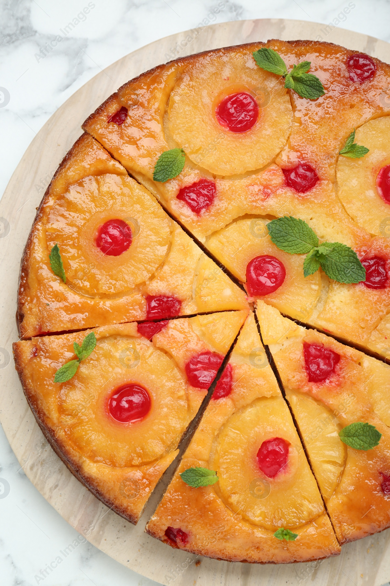 Photo of Delicious cut pineapple pie with cherry and mint on white marble table, top view