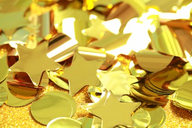 Beautiful golden confetti on shiny glitter, closeup