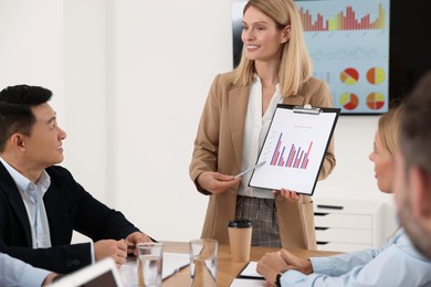 Businesswoman showing chart on meeting in office
