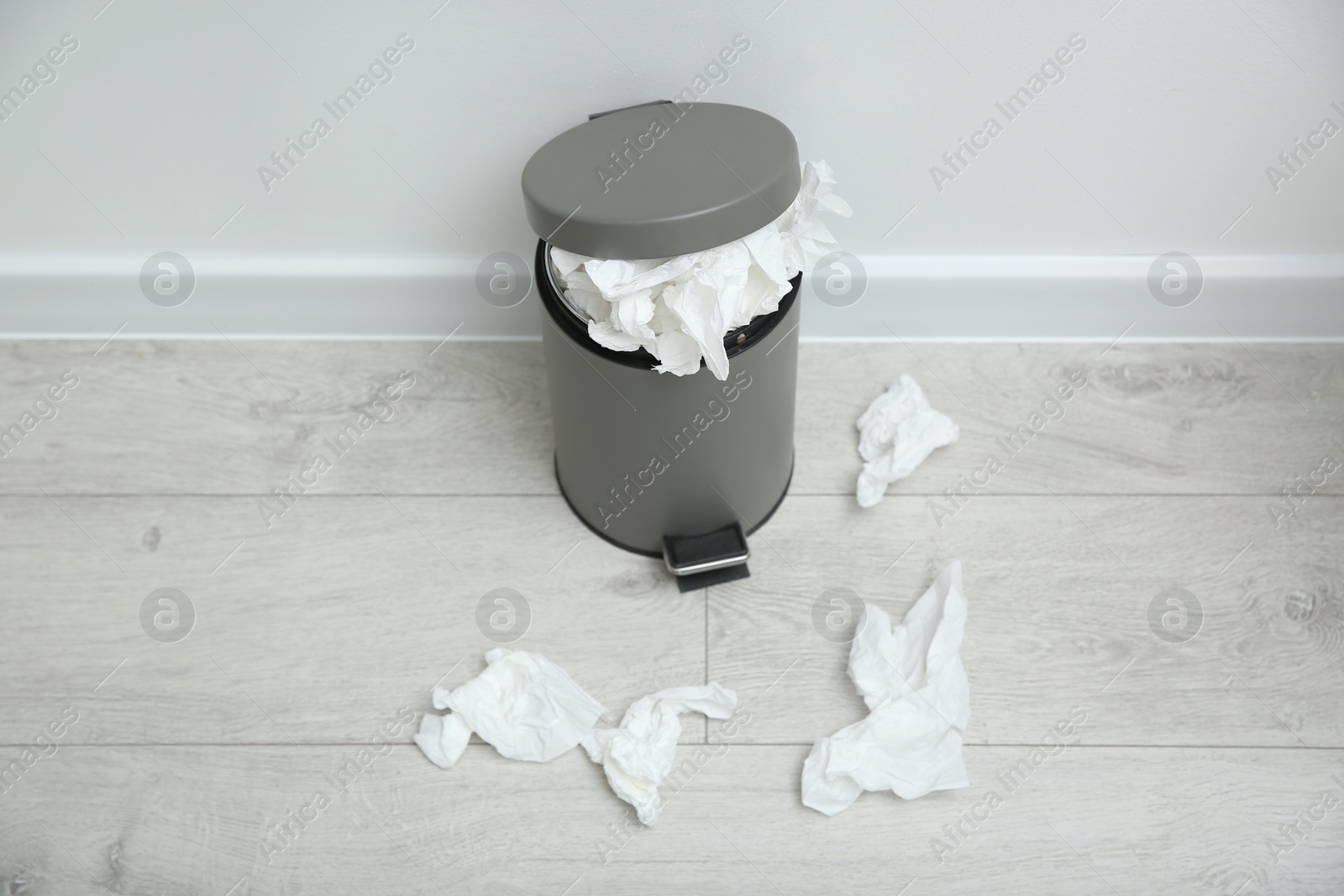 Photo of Used paper tissues and trash can on wooden floor