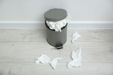 Photo of Used paper tissues and trash can on wooden floor