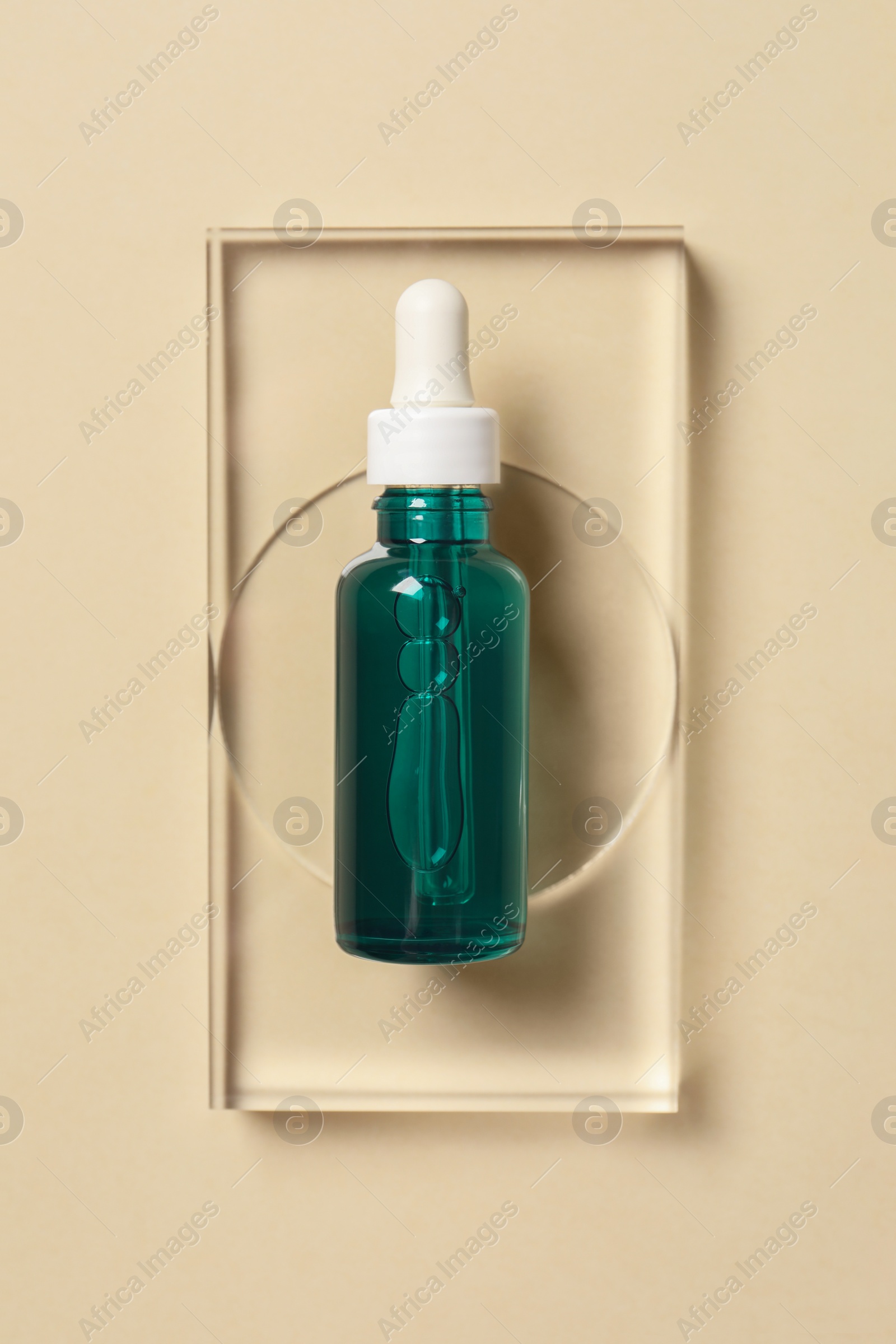 Photo of Bottle of cosmetic serum on beige background, top view