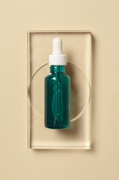 Photo of Bottle of cosmetic serum on beige background, top view