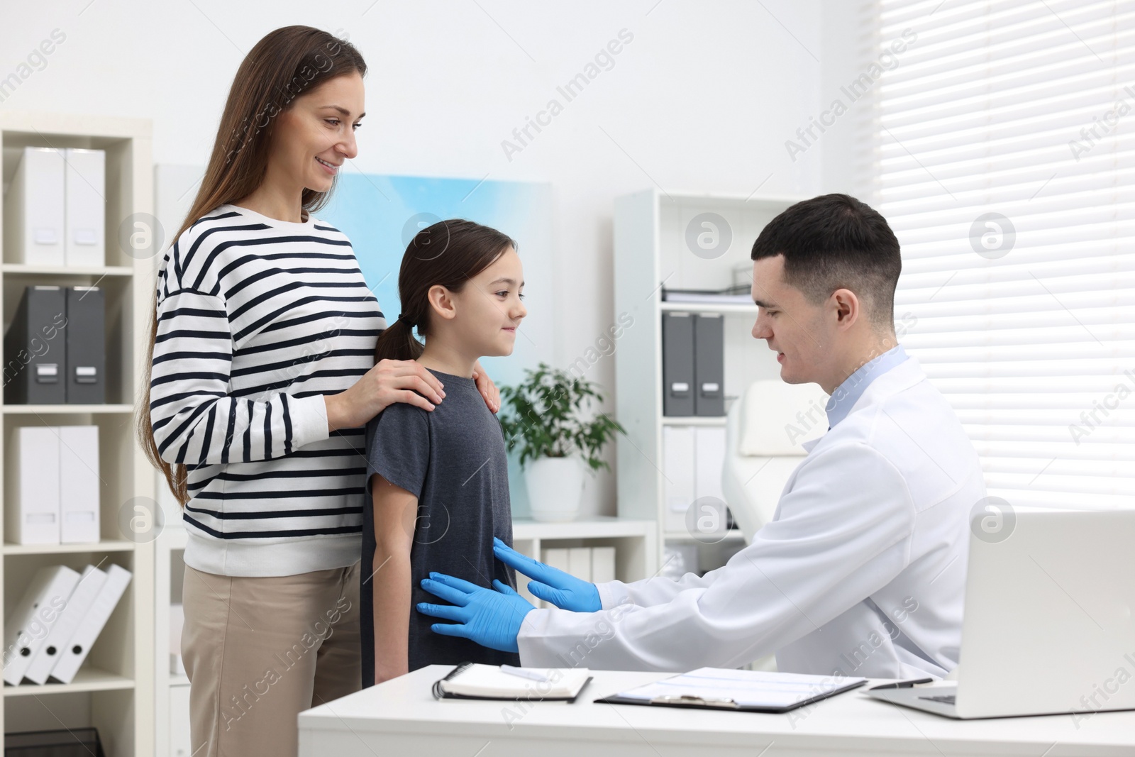 Photo of Gastroenterologist examining girl with stomach ache in clinic