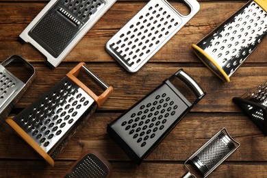 Different modern graters on wooden table, flat lay