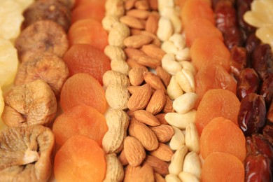 Photo of Different tasty nuts and dried fruits as background, closeup