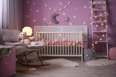 Photo of Baby room interior with crib near color wall