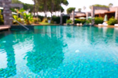 Luxury resort with outdoor swimming pool and sun loungers on sunny day, blurred view