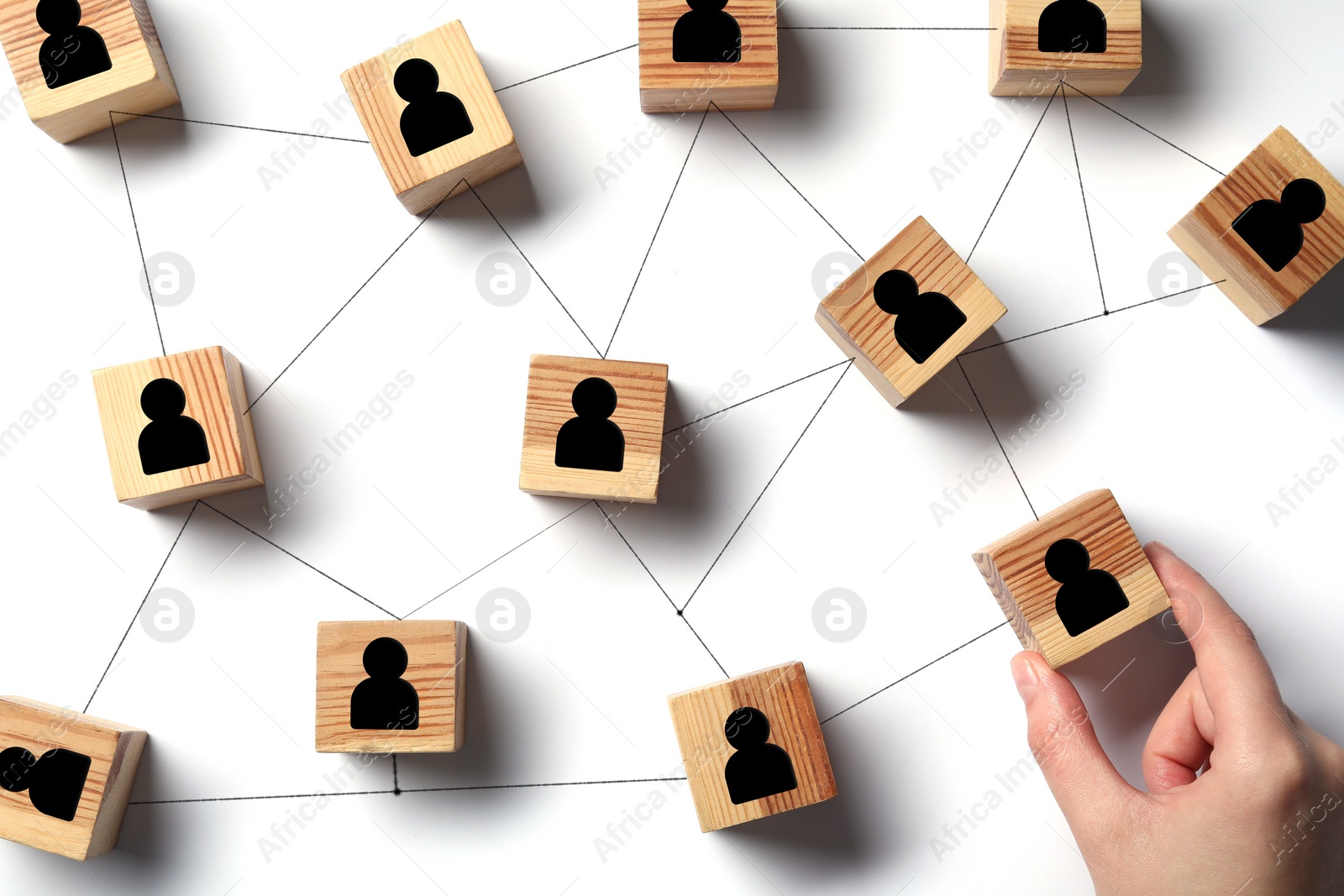 Image of Teamwork. Woman arranging wooden cubes with human icons linked together symbolizing cooperation at white table, top view