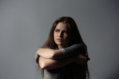 Depressed young woman on gray background