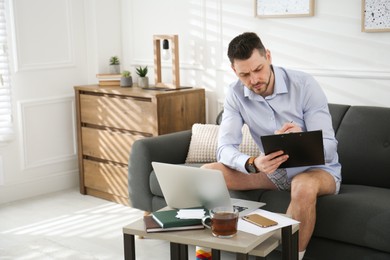 Photo of Businessman wearing shirt and underwear during video call at home