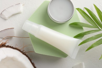 Photo of Lip balms, coconut and leaves on white background, flat lay