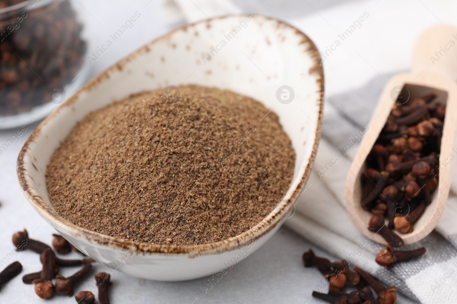 Photo of Aromatic clove powder and dried buds on light table, closeup