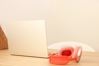 Photo of Modern laptop and headphones on wooden table. Space for text