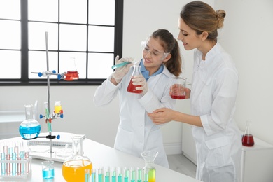 Photo of Teacher with pupil making experiment in chemistry class