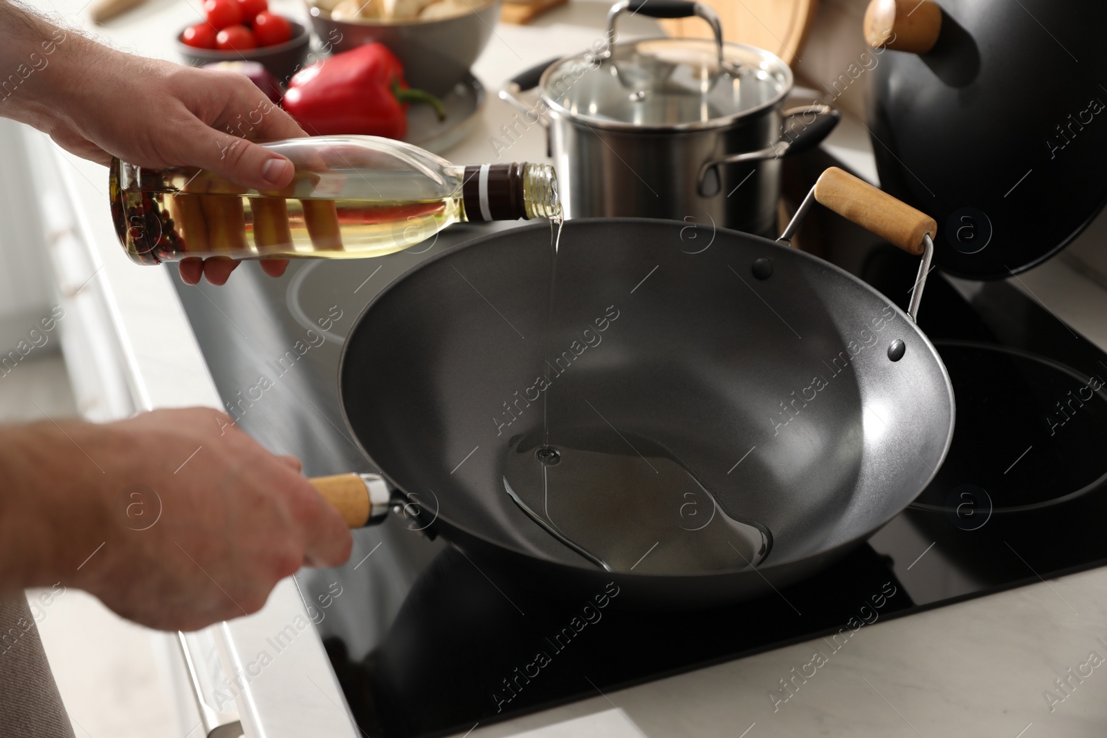 Photo of Man pouring cooking oil into frying pan in kitchen, closeup