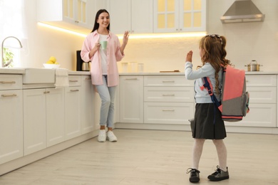 Photo of Little girl with backpack and mother in kitchen. Getting ready for school