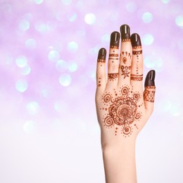 Image of Woman with henna tattoo on hand against blurred lights, bokeh effect. Space for text