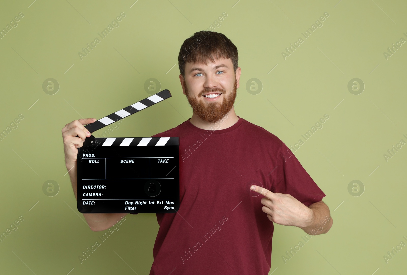 Photo of Making movie. Smiling man pointing at clapperboard on green background