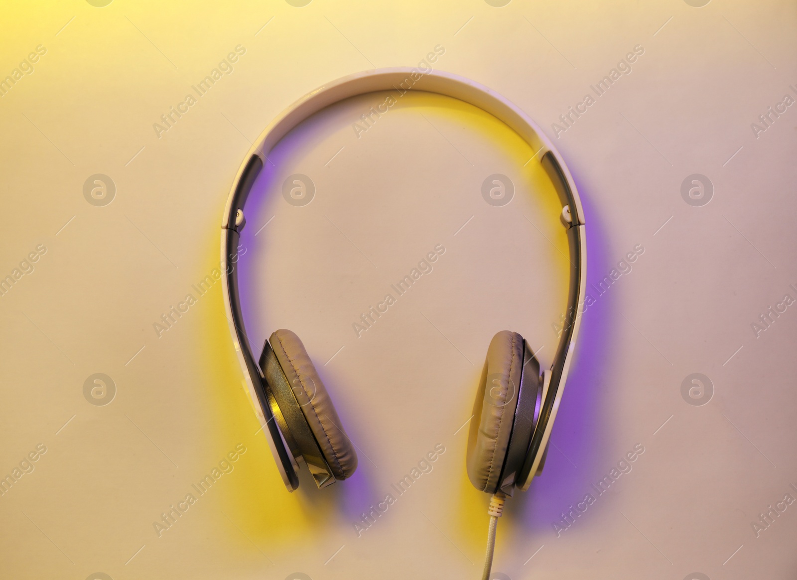 Photo of Stylish modern headphones with earmuffs on color background, top view