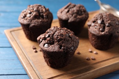 Photo of Delicious chocolate muffins on blue wooden table, closeup