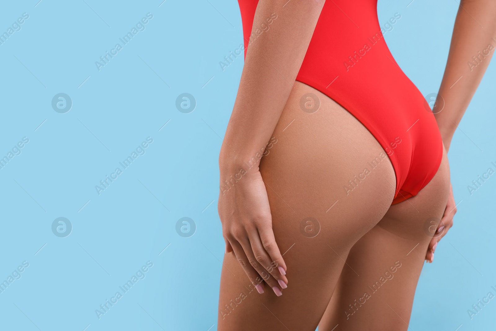 Photo of Young woman in stylish swimsuit on light blue background, closeup. Space for text