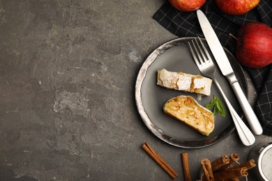 Photo of Delicious strudel, cinnamon and fresh apples on grey table, flat lay. Space for text