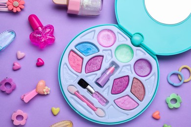 Photo of Children's kit of makeup products and accessories on violet background, flat lay