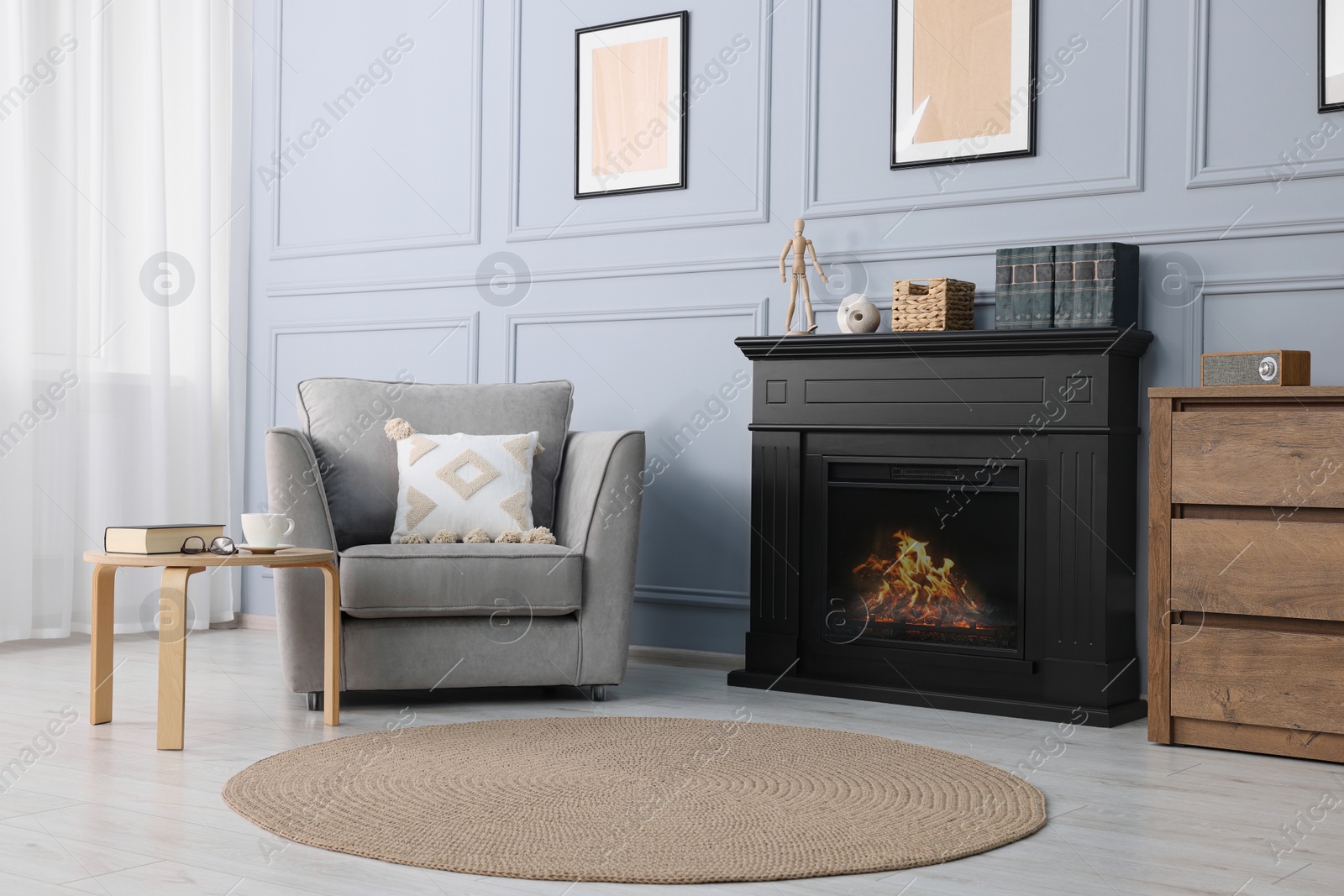 Photo of Black stylish fireplace near armchair in cosy living room