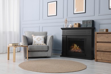 Photo of Black stylish fireplace near armchair in cosy living room