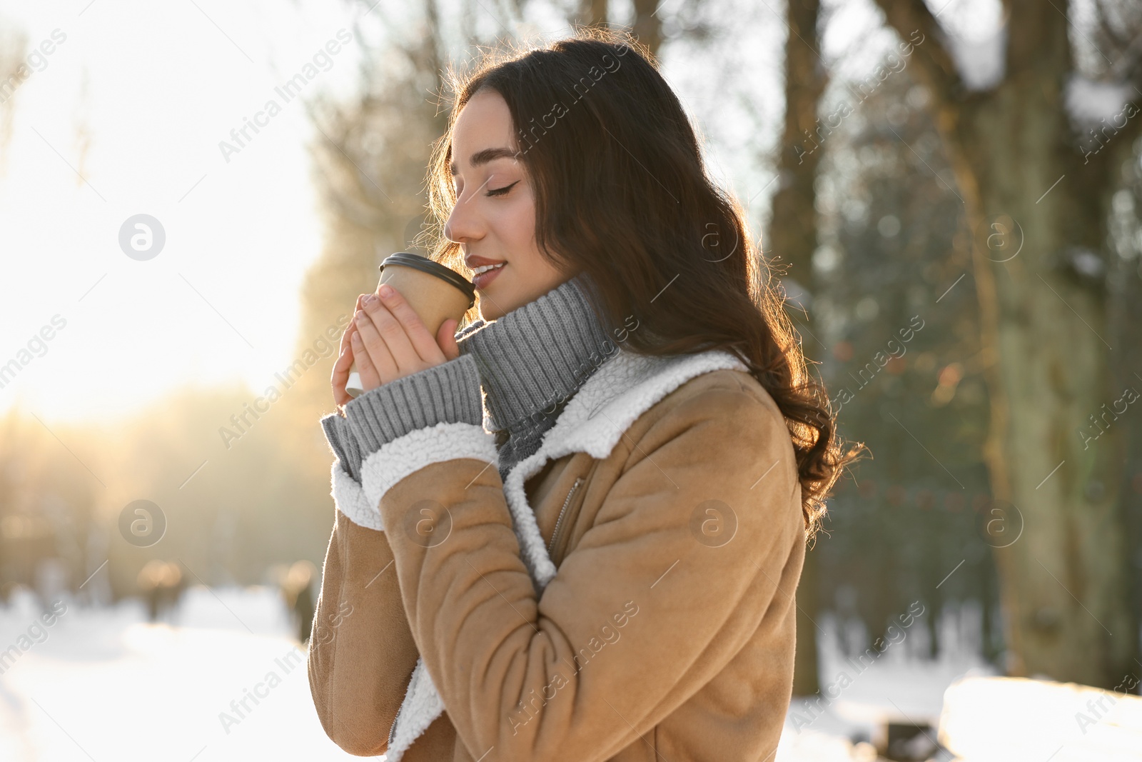 Photo of Portrait of beautiful woman drinking coffee in snowy park