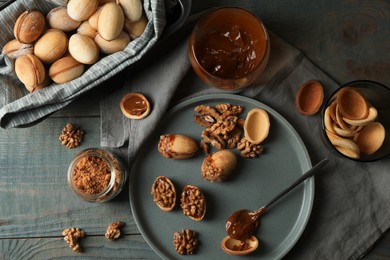 Photo of Freshly baked homemade walnut shaped cookies with nuts and boiled condensed milk on wooden table, flat lay