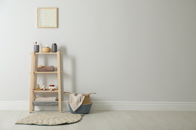 Photo of Wooden shelving unit with toiletries near white wall indoors, space for text. Bathroom interior element