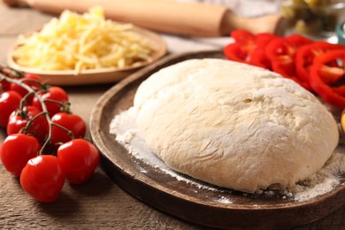 Photo of Pizza dough and products on wooden table, closeup