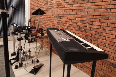 Photo of Musical instruments near red brick wall indoors, focus on synthesizer