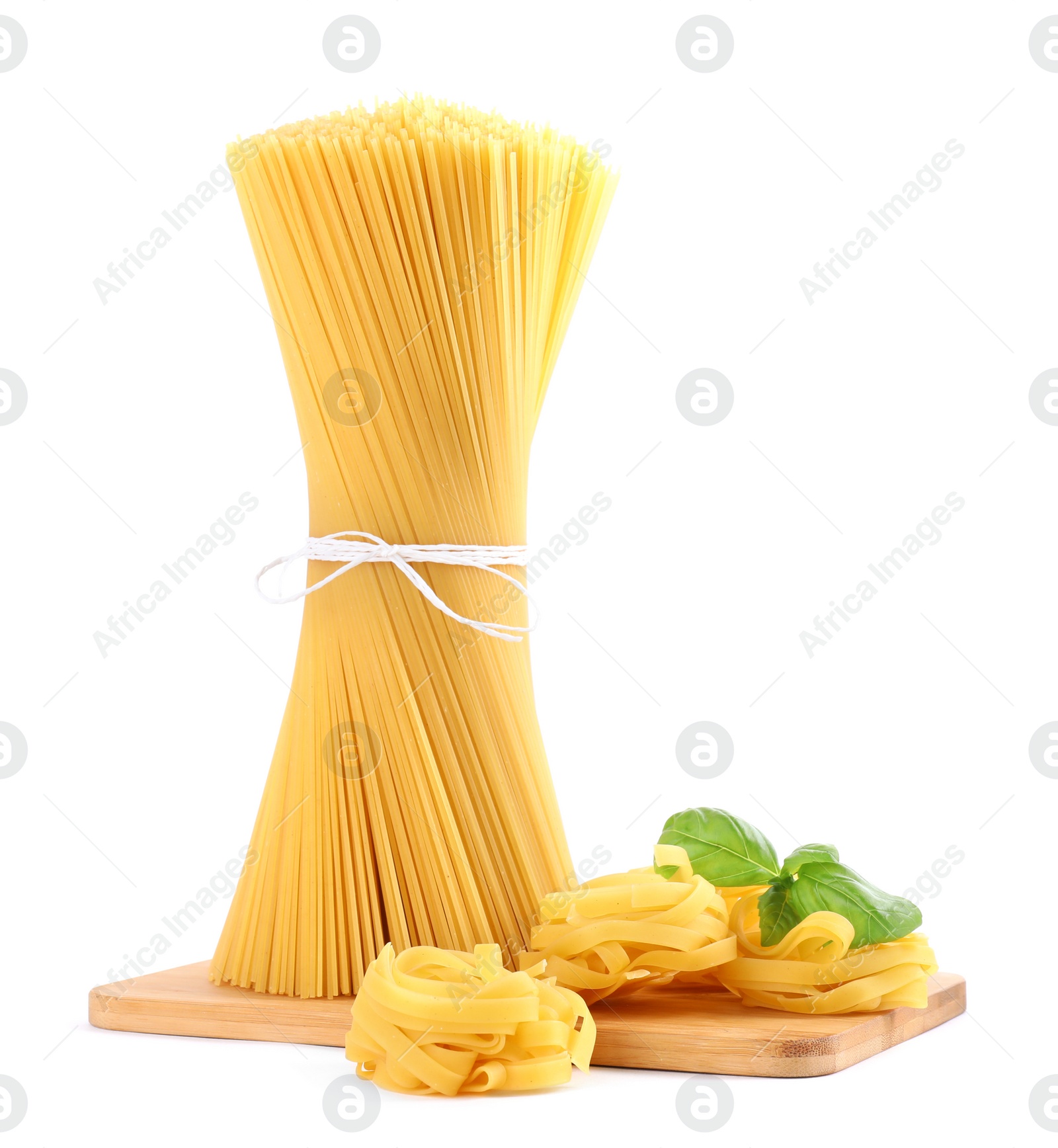 Photo of Wooden board with spaghetti, tagliatelle pasta and basil leaves isolated on white