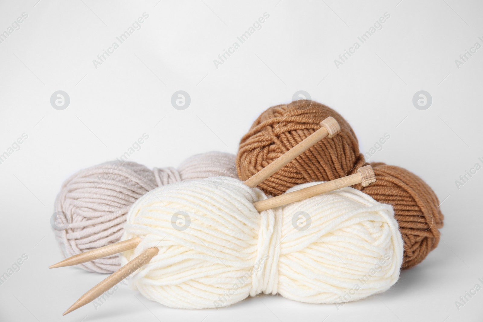 Photo of Soft woolen yarns and knitting needles on white background