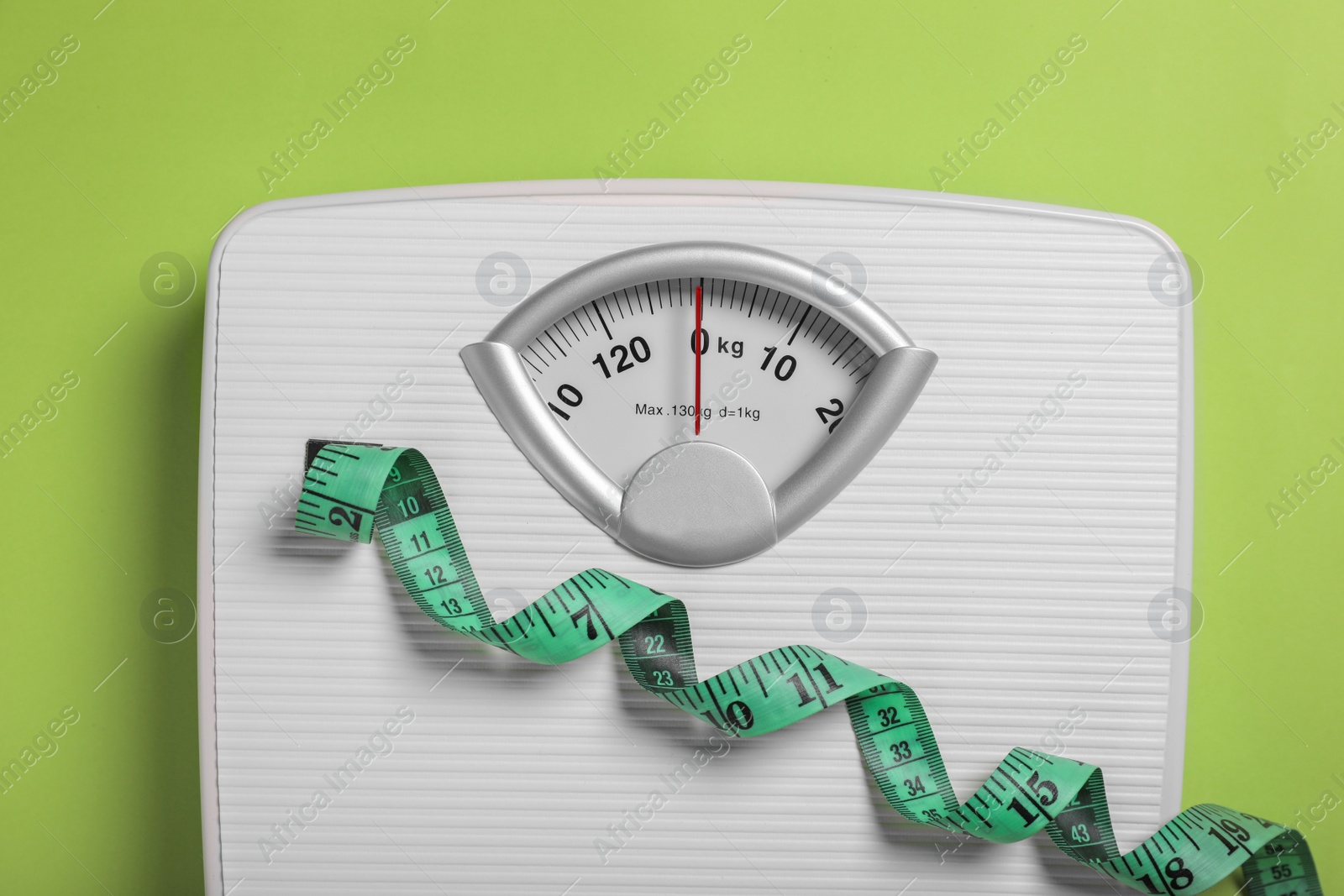 Photo of Weight loss concept. Scales and measuring tape on green background, top view