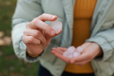 Photo of Woman holding hail grains after thunderstorm outdoors, closeup