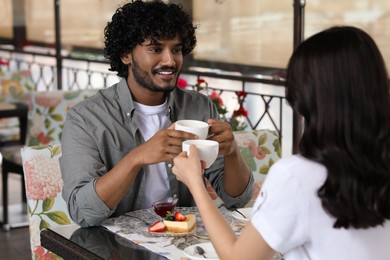 Photo of International dating. Lovely couple enjoying tasty coffee in cafe