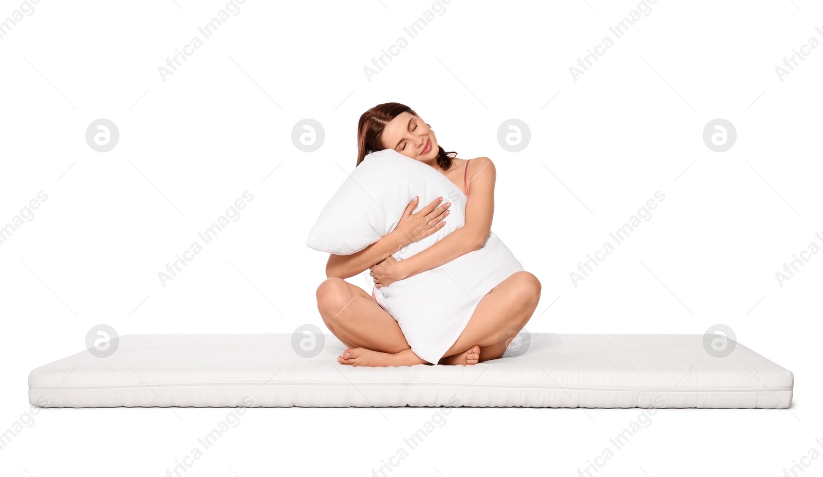 Photo of Young woman on soft mattress holding pillow against white background
