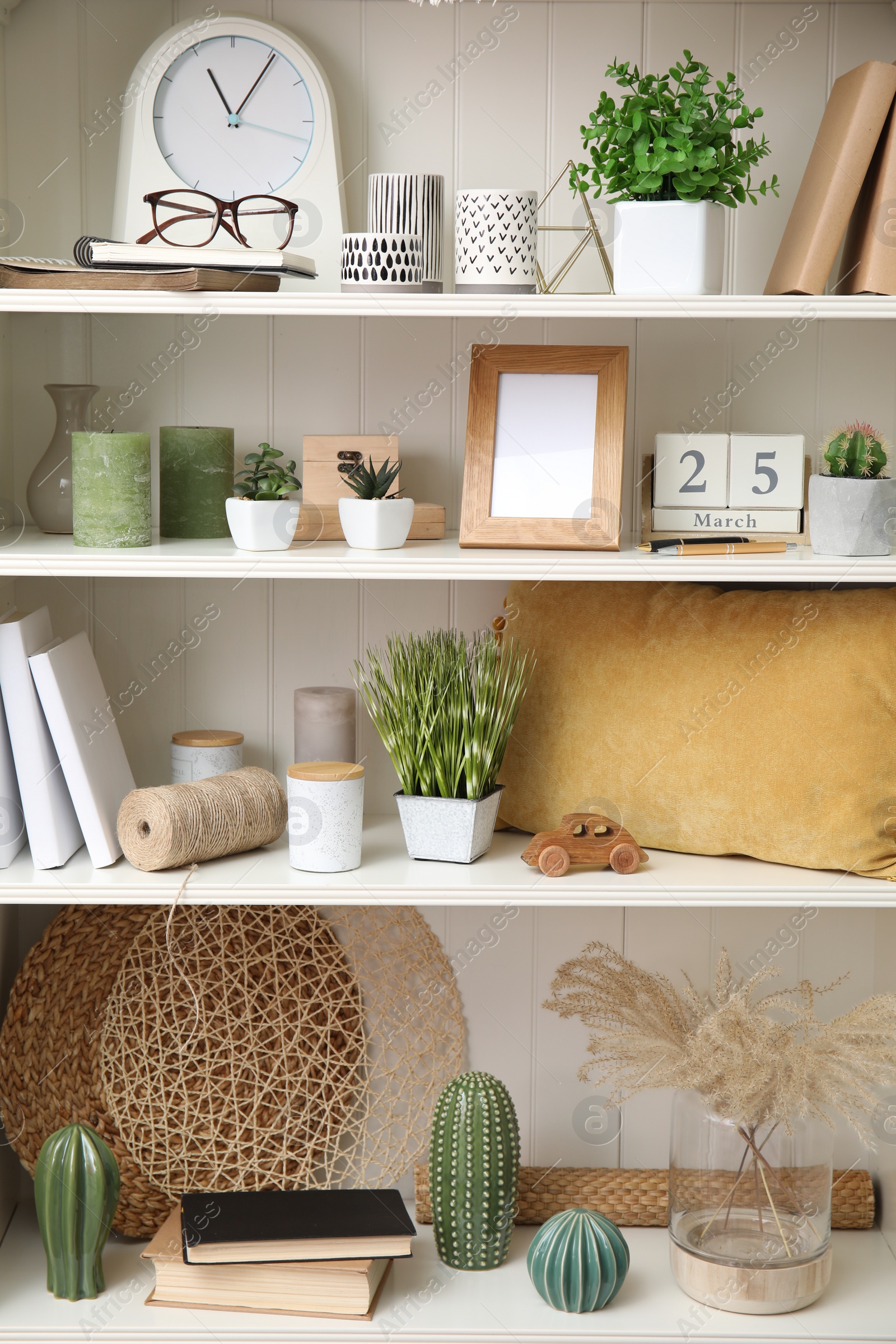 Photo of White shelving unit with plants and different decorative stuff