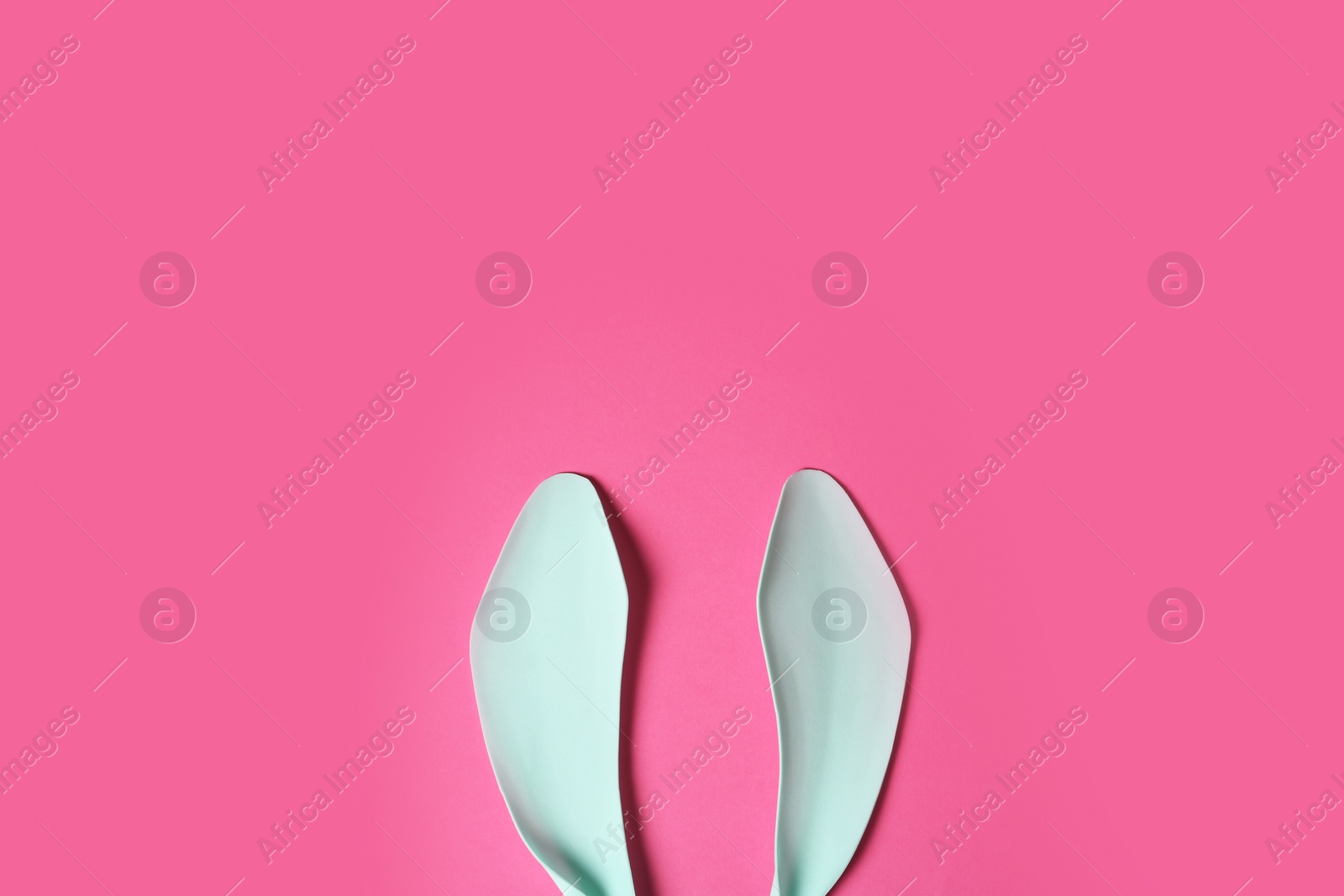 Photo of Funny Easter bunny ears on color background, top view with space for text