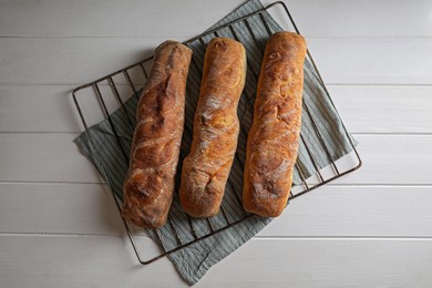 Fresh crispy ciabattas on white wooden table, top view