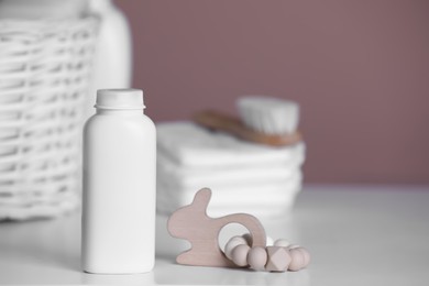 Bottle of baby cosmetic product and wooden toy on white table. Space for text