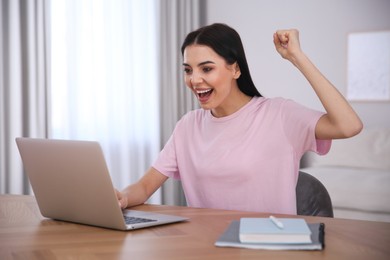 Photo of Emotional woman participating in online auction using laptop at home