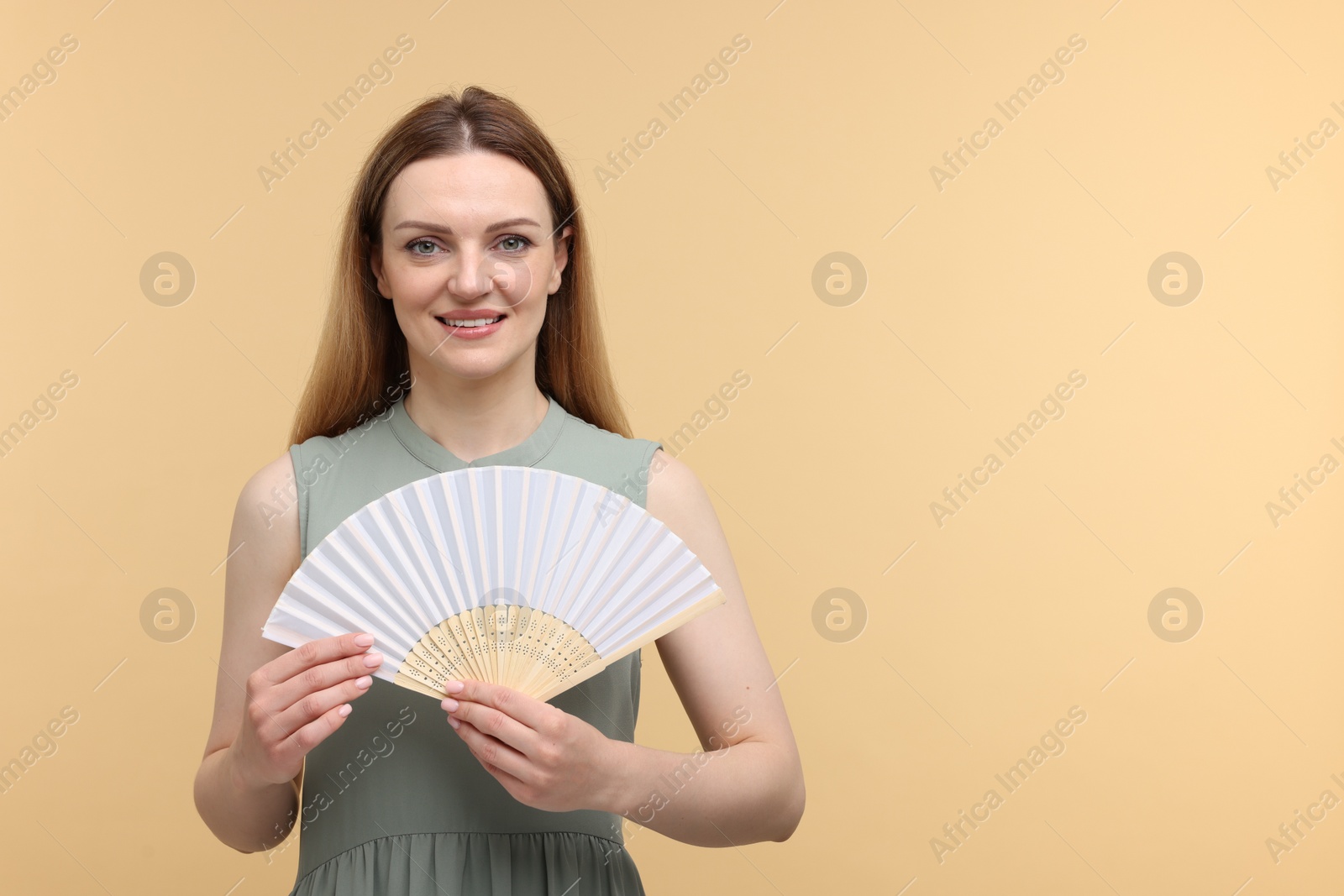 Photo of Happy woman with hand fan on beige background, space for text