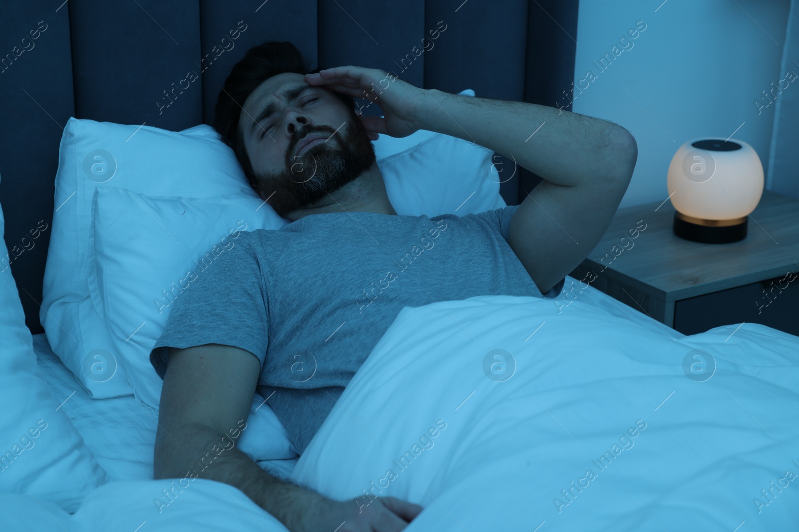 Photo of Man suffering from headache in bed at night